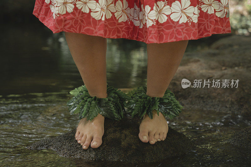 一个波利尼西亚舞者在河边岩石上光脚的细节照片。