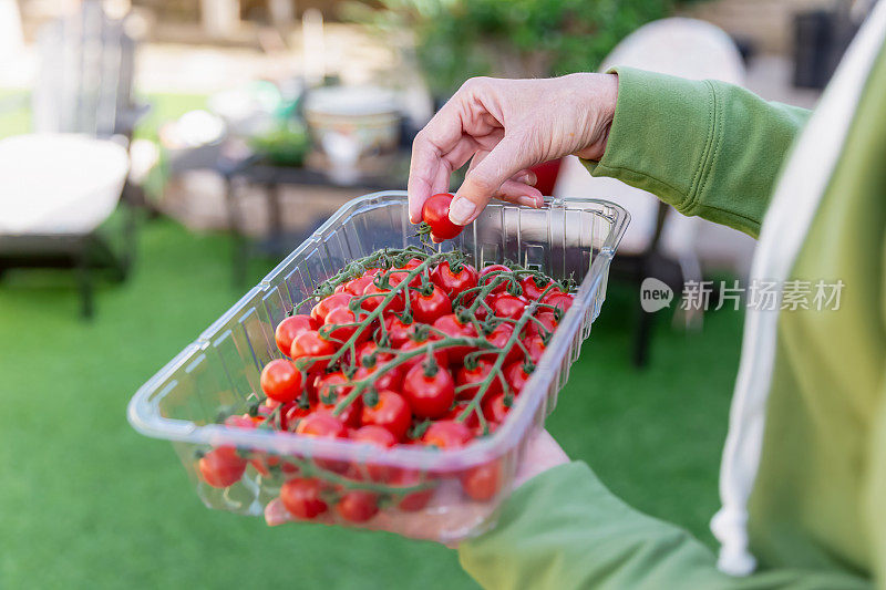 一个女人拿着一个装着西红柿的塑料容器