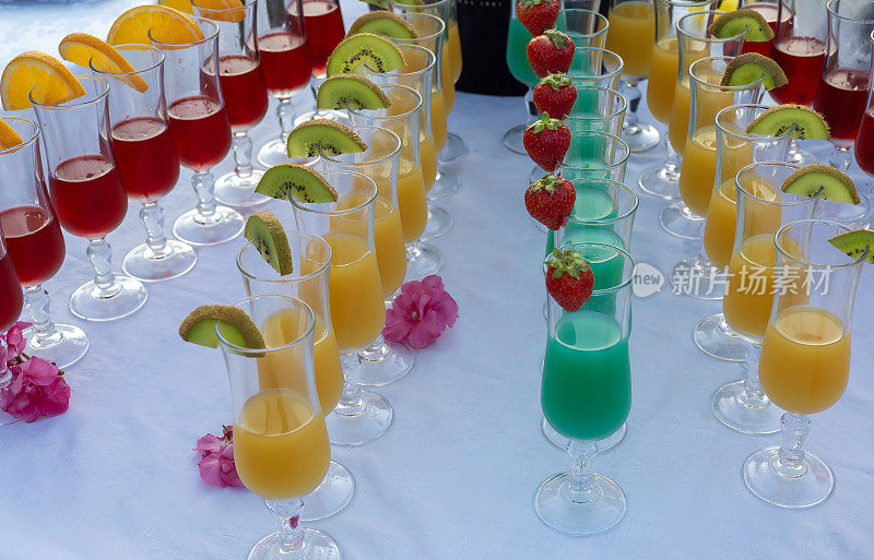 装有不同口味和颜色开胃酒的水晶酒杯。把水果放在杯子边上作为装饰品。不同颜色的果汁。夏天比赛