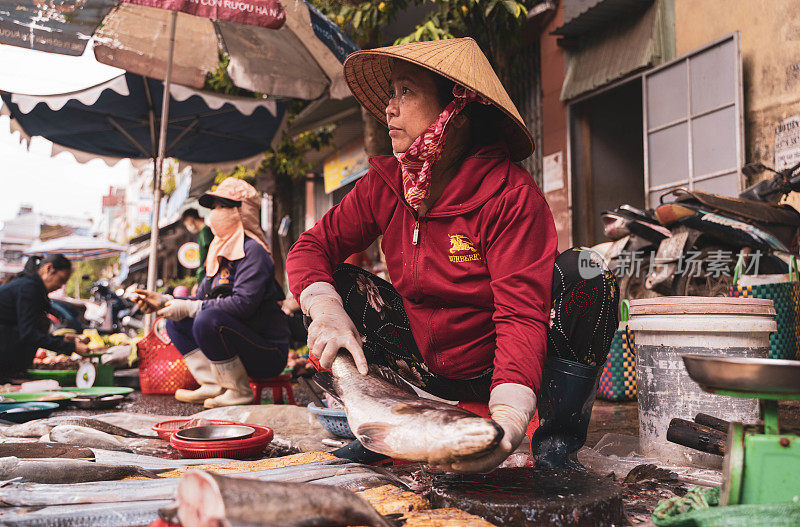 一位老妇人在胡志明市的街市上卖鱼