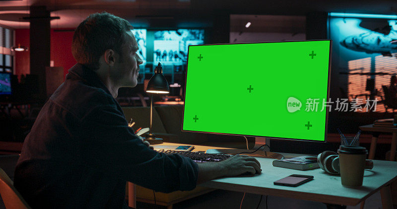 有创意的人坐在办公桌前使用桌面电脑的肖像，绿屏模型。在游戏开发初创公司工作的男性专家，负责完成项目细节