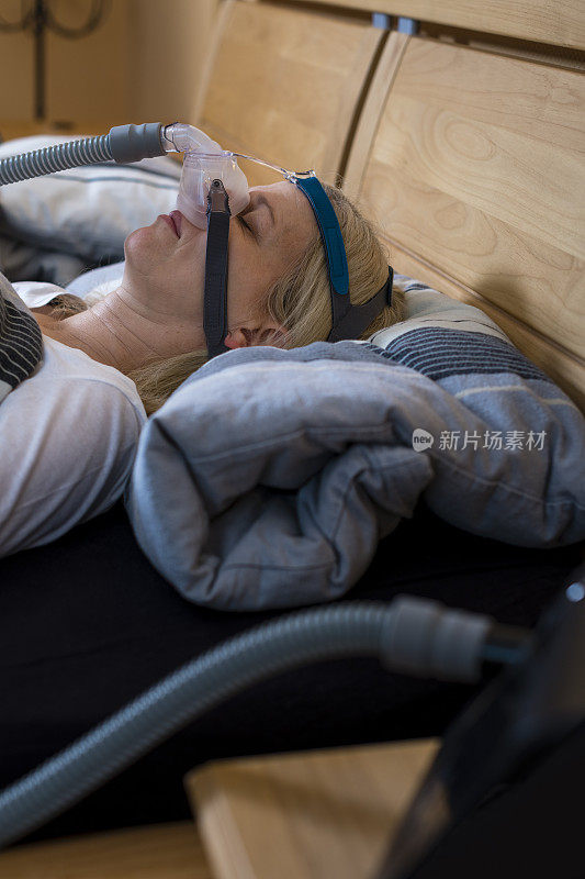 因为阻塞性睡眠呼吸暂停而戴着呼吸面罩睡觉的女人