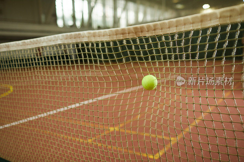 特写的绿色网球打到网被认为是在室内球场，网球游戏的背景