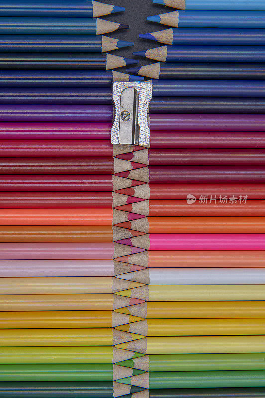 把彩色铅笔放在一起，用卷笔刀作为拉链扣件获得拉链效果