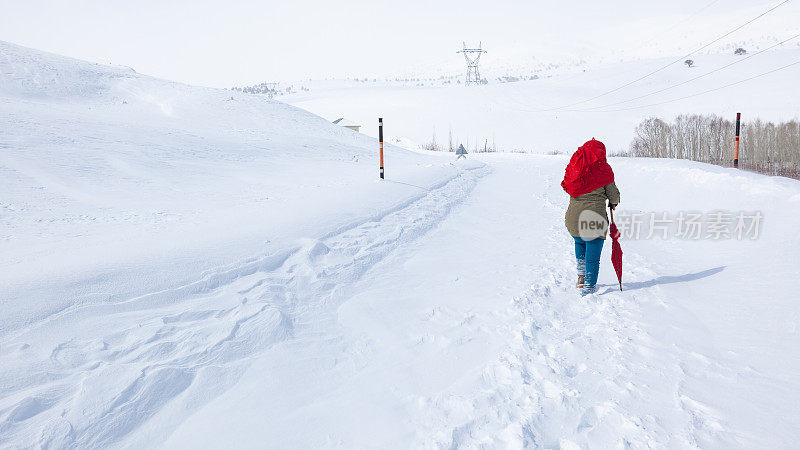 成年妇女穿着暖和的衣服在雪地上行走在农村