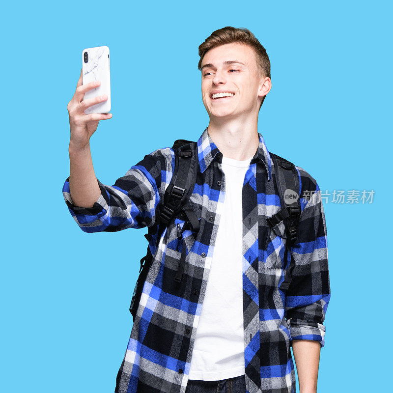 白人年轻男性摄影穿着裤子和使用智能手机