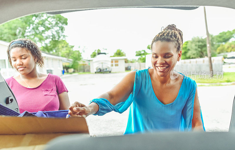 非裔美国母亲和女儿往家里的车上装东西
