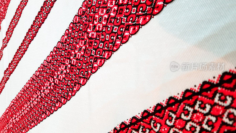 乌克兰民间手工刺绣。用红黑线绣在白色织物上的装饰品。用黑色和红色的线绣的装饰品。白色织物上的乌克兰民族民间刺绣