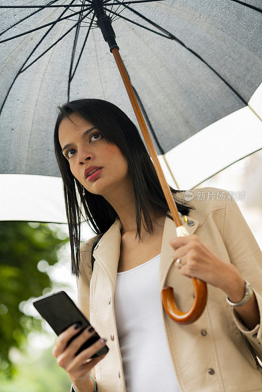 一名年轻女子在下雨的时候在街上等他的优步