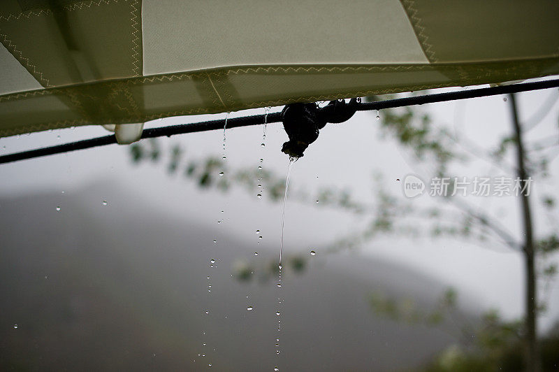 雨水从大帐篷的一侧顺着绳索滴落下来