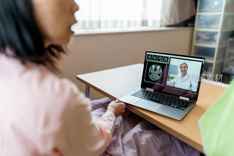 远程保健和访问护理-妇女在家里的笔记本电脑上与医生视频聊天