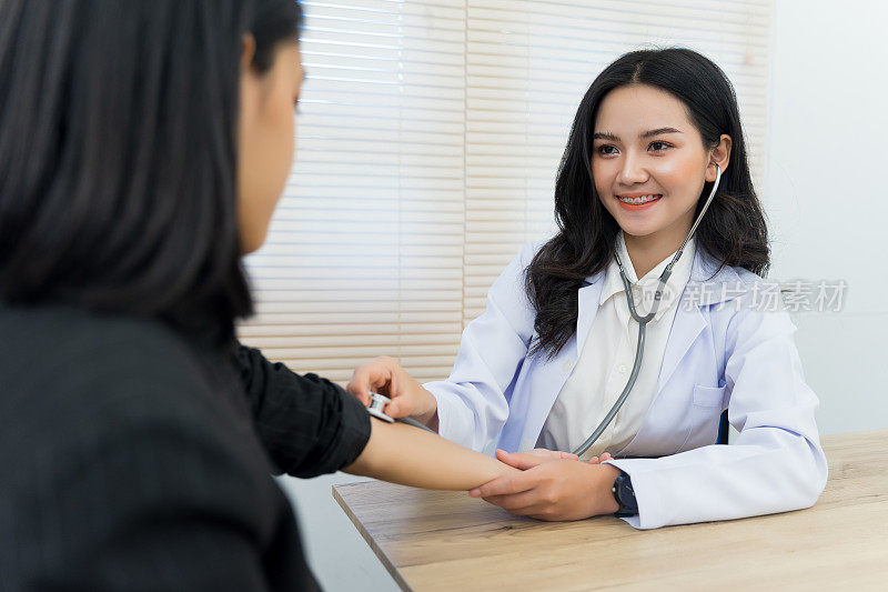 年轻的亚洲女医生使用听诊器对成年女性病人的病情和症状进行检查和诊断。医学保健理念。医生和病人。