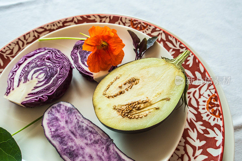 白色台布上，紫菜、紫薯、红白菜、茄子，点缀桔黄色旱金莲花