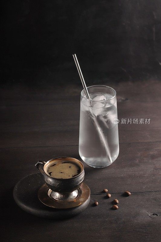一杯黑咖啡和一杯冷水，背景是深色的木头