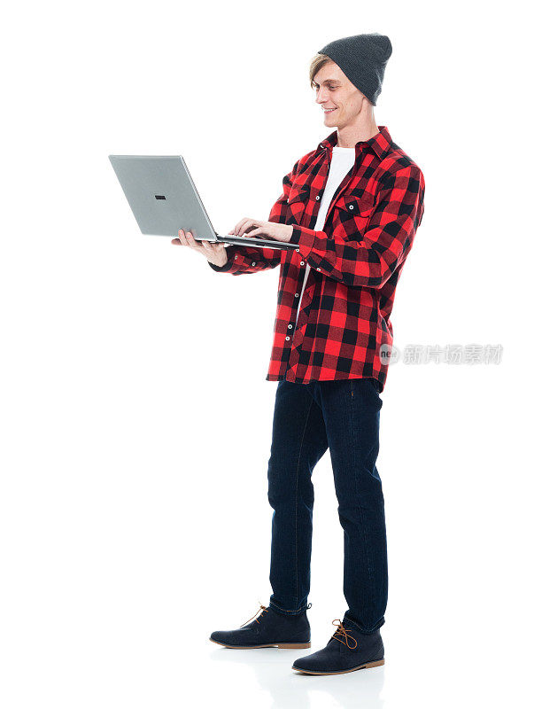 白人潮男穿着t恤站在白色背景前，用着笔记本电脑