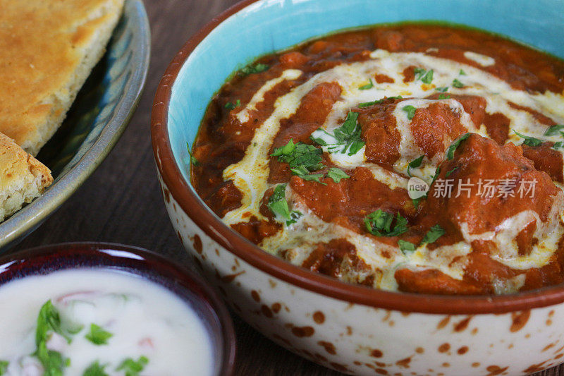 这是一碗自制的咖喱鸡，配上印度烤饼和raita(酸奶酱)的特写画面