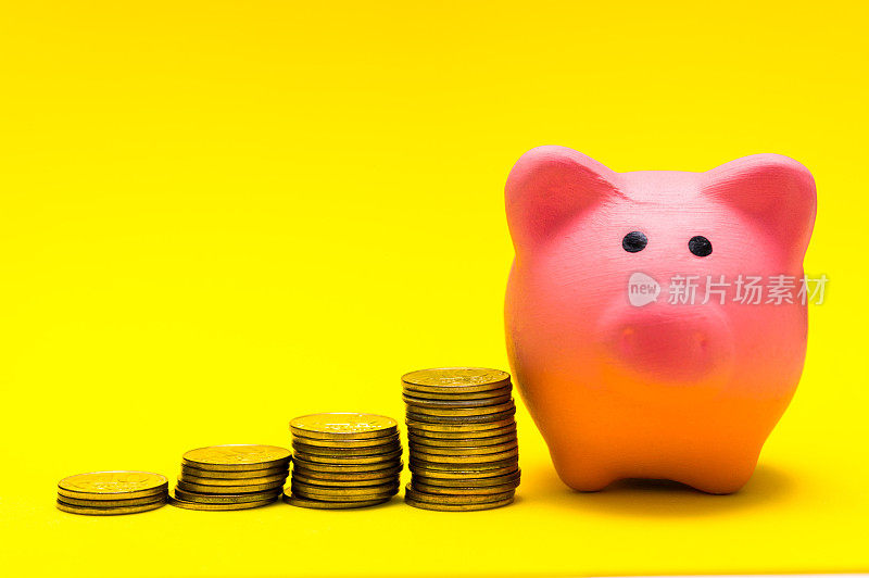 粉红色的储蓄罐在黄色的背景上，与一堆硬币显示增长。52、观念储蓄，理财理财。