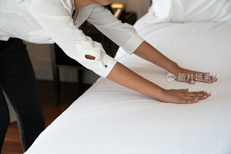 在酒店客房服务部详细整理床铺。