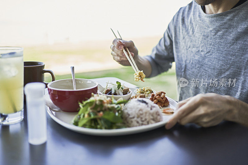 一名日本男子在一家素食咖啡馆的露台上吃素食午餐。