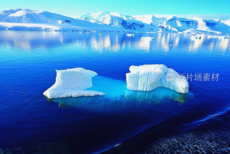 海面像一面蓝色的镜子。冰山的倒影增添了一种神秘感。