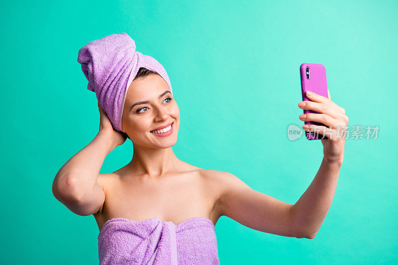 美丽的女士拿着电话自拍美丽博客视频穿紫罗兰毛巾孤立的蓝绿色背景的照片