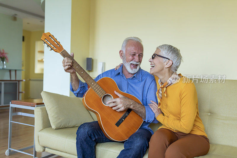 一位快乐的退休老人正在为他美丽的妻子弹吉他，他的妻子喜欢轻松的音乐。