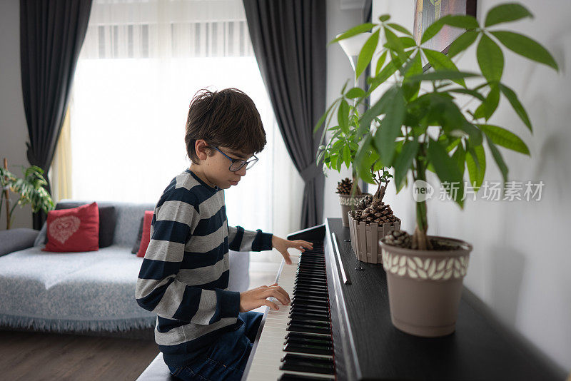 小男孩在家里的客厅里弹钢琴。