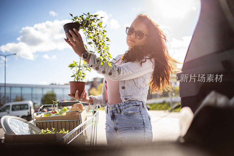 一位漂亮的年轻女子在超市买完东西，买了一些蔬菜和漂亮的花。