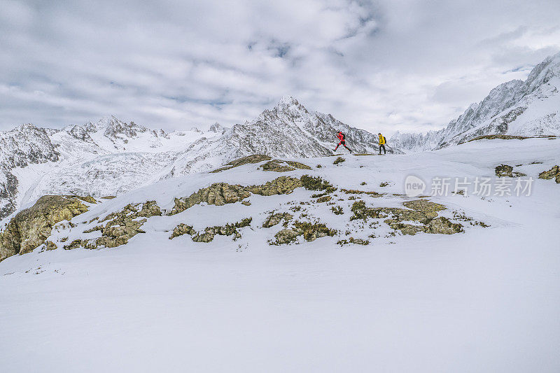 徒步旅行者沿着雪山中的山脊蹦蹦跳跳