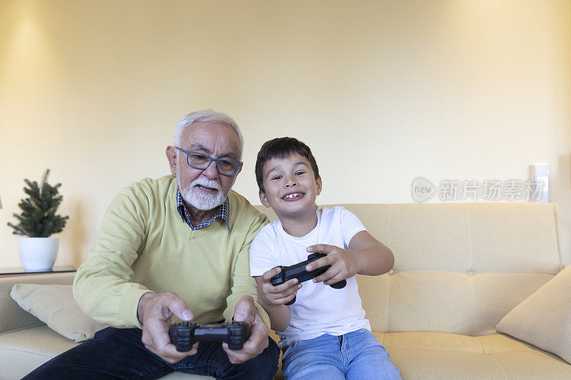 一个可爱的小孩和他的爷爷在家里玩电子游戏。