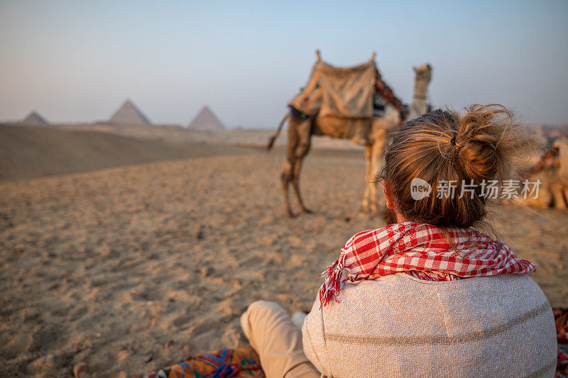 一个人在吉萨金字塔边看日落，他眺望着撒哈拉沙漠