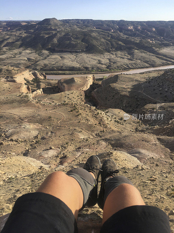 POV经过山地自行车手的腿到峡谷和下面的河流