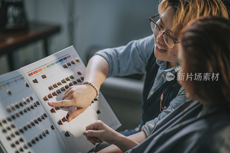 发廊亚洲华人女性发型师展示发色图给顾客讨论并推荐