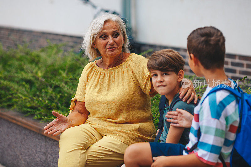 一位老太太正坐在她的孙辈旁边和他们说话。