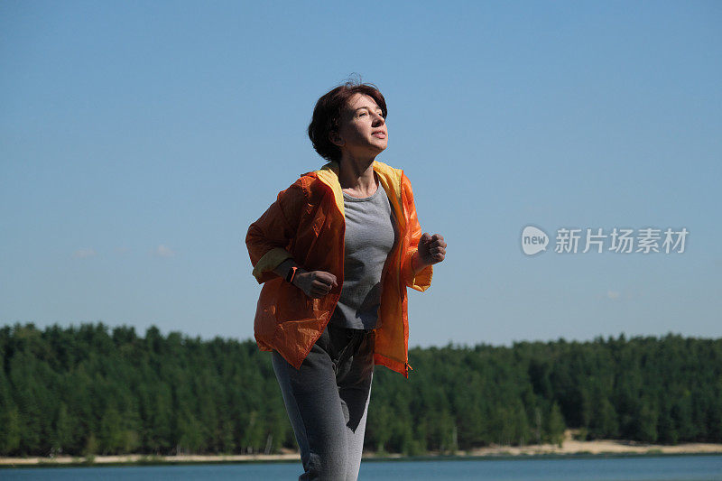 成熟的女人在夏日的自然公园里奔跑