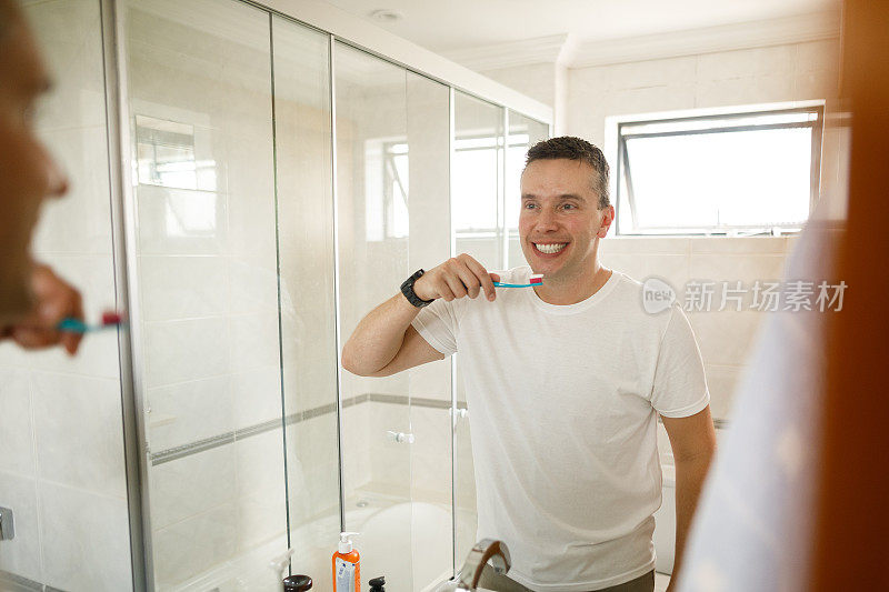 男子微笑着对着镜子检查自己的牙齿
