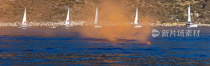 蓝色海洋中的橙色烟雾弹。背景帆船