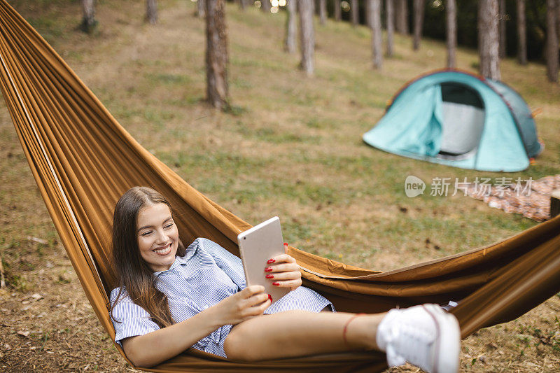 一名女子在森林里休息和露营时使用数码平板电脑