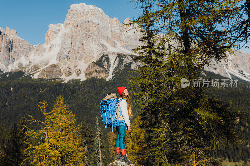 一名女游客背着她的狗在阿尔卑斯山的白云石徒步旅行