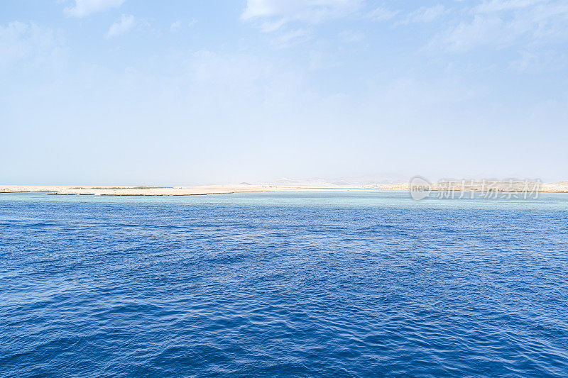蓝天白云，碧水蓝天。海滩在地平线上。埃及沙姆沙伊赫海岸线，碧海碧水