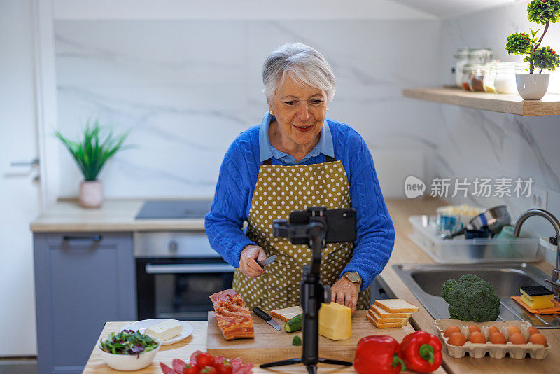 妇女准备食物配方，同时在线流与移动智能手机摄像头为网络厨房大师班频道