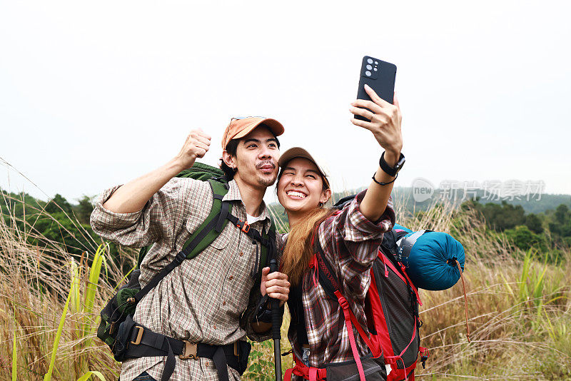 抓拍小情侣徒步冒险，用手机拍下登山时的照片，冒险旅行的生活方式，背包旅行者登山