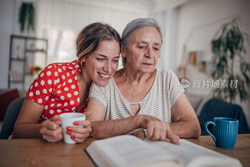 快乐的奶奶和十几岁的孙女在家里享受早餐咖啡，聊天