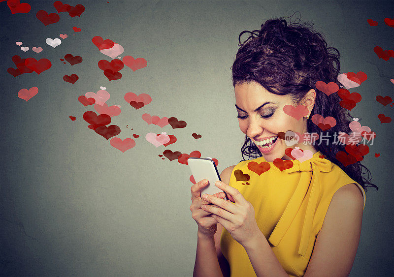 美丽幸福的女人用红心在手机上发爱情短信