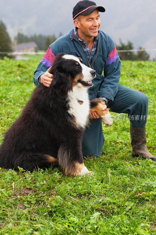 一位瑞士农夫拿着一只伯尔尼山犬的爪子