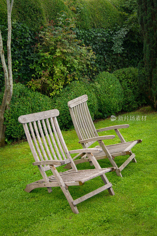 两个木制躺椅在一个正式的花园