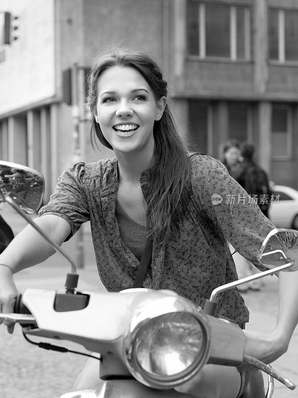 骑着踏板车微笑的年轻女子