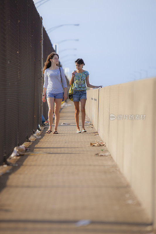 两个女孩正走过工业区的一座桥