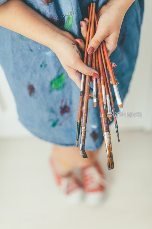 一个拿着画笔的艺术家沾满颜料的手