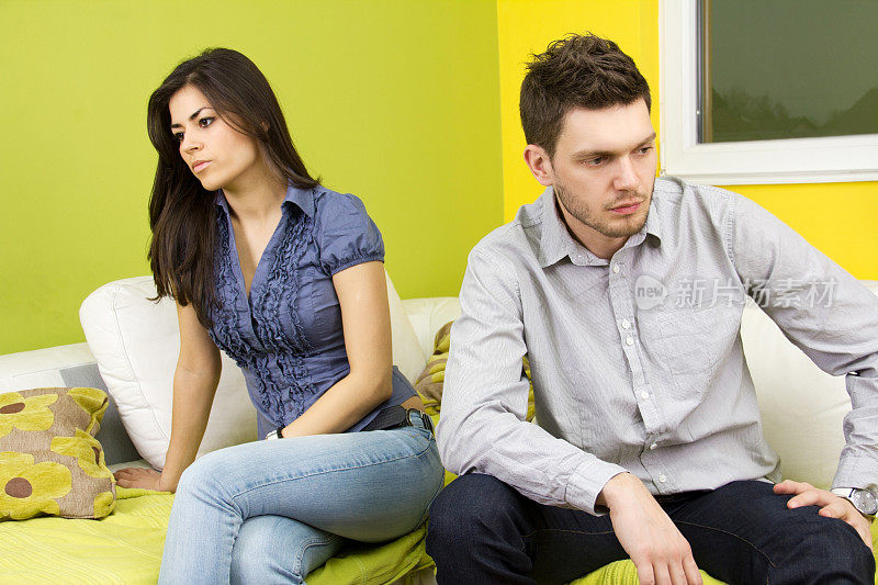 一对不开心的年轻夫妇坐在客厅里。